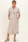 woman wearing a beige and blue striped maternity dress with puff sleeves and a tie waist, holding her baby bump