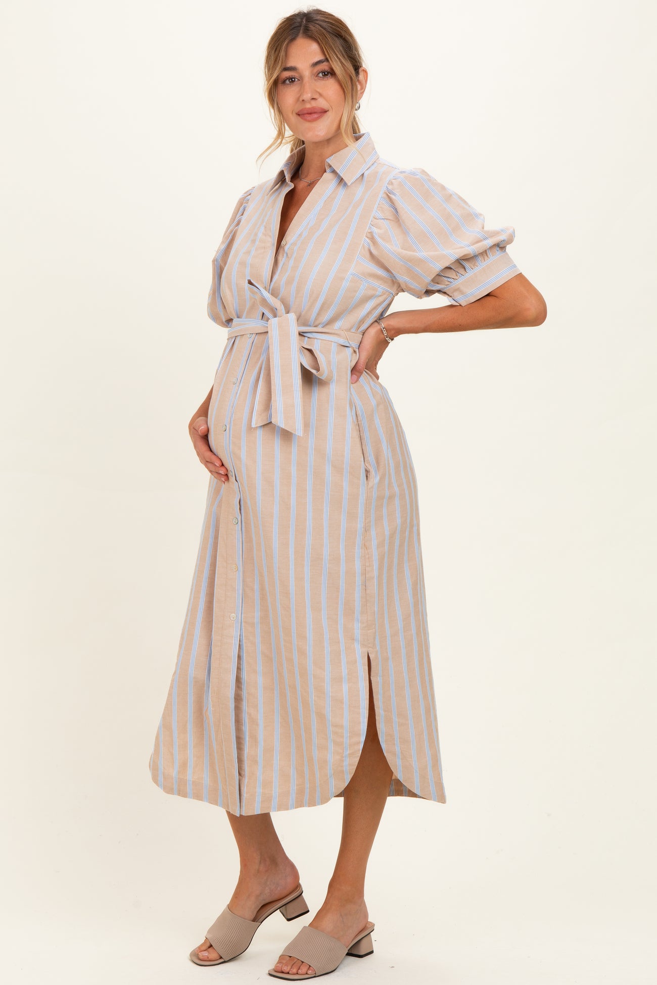 woman wearing a beige and blue striped maternity dress with puff sleeves and a tie waist, showing her baby bump
