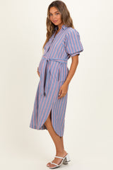 woman wearing a blue and pink striped maternity dress with short puff sleeves and a tie belt, highlighting her baby bump