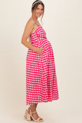woman wearing a pink and white checkered maternity dress with pockets, showcasing her baby bump and styled with a headband