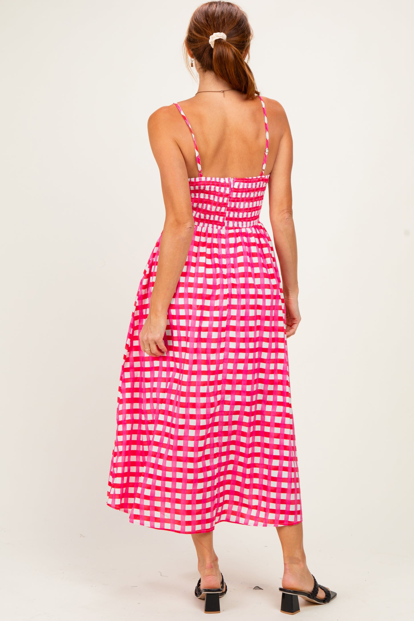 woman wearing a pink and white checkered midi dress with spaghetti straps and a fitted bodice, shown from the back