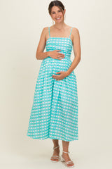 woman wearing a turquoise gingham maternity dress with spaghetti straps and a visible baby bump
