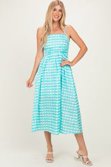 woman wearing a light blue and white checkered midi dress with spaghetti straps and a fitted bodice