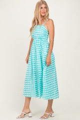 woman wearing a turquoise gingham midi dress with spaghetti straps and a cinched waist