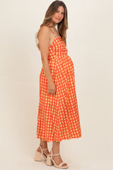 woman wearing a red and white checked maternity dress with spaghetti straps and a fitted waist, showing baby bump