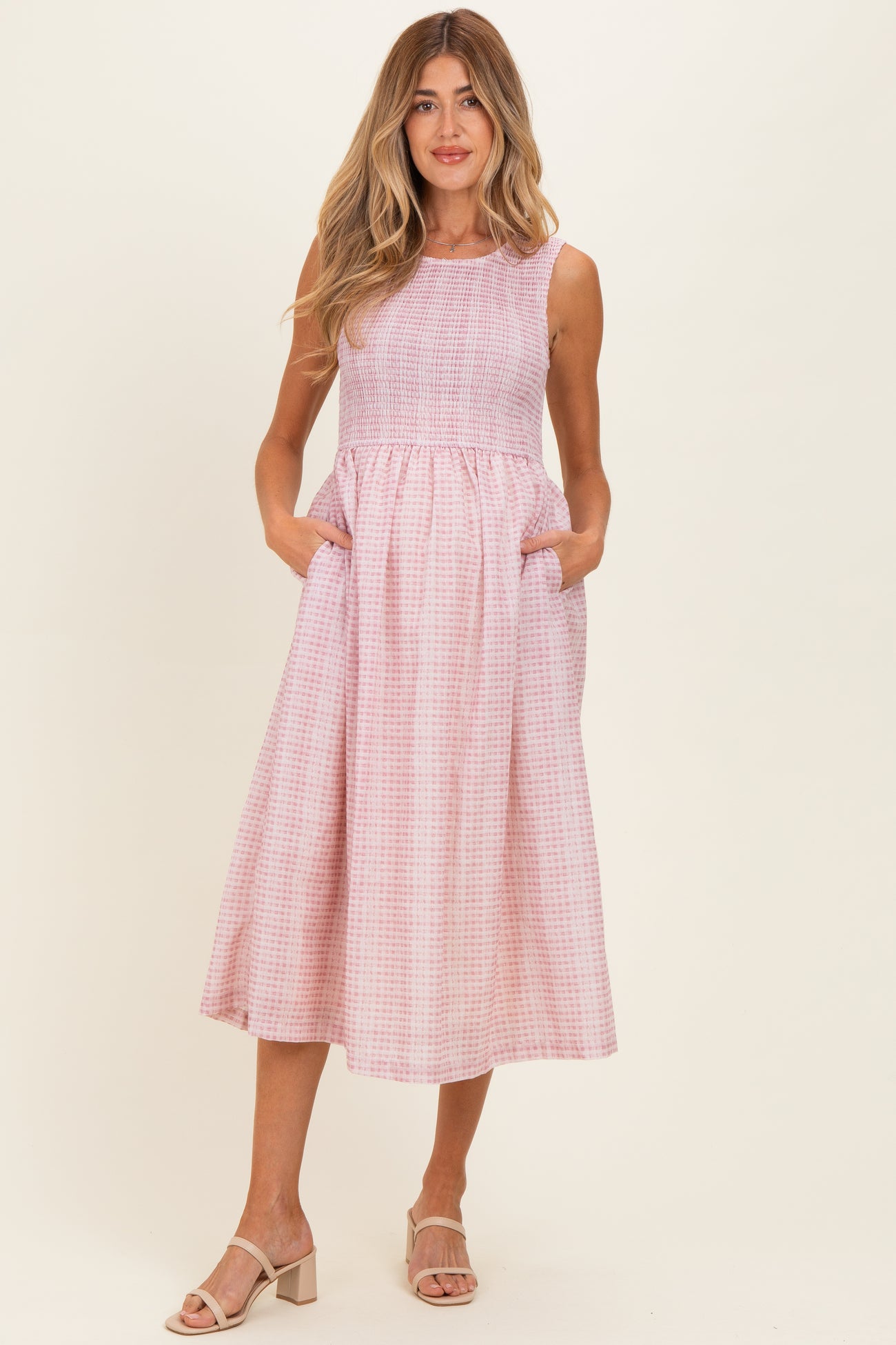woman wearing a pink and white gingham maternity dress with pockets and a flowy skirt