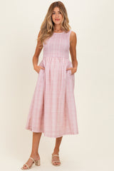woman wearing a pink and white gingham maternity dress with pockets and a flowy skirt