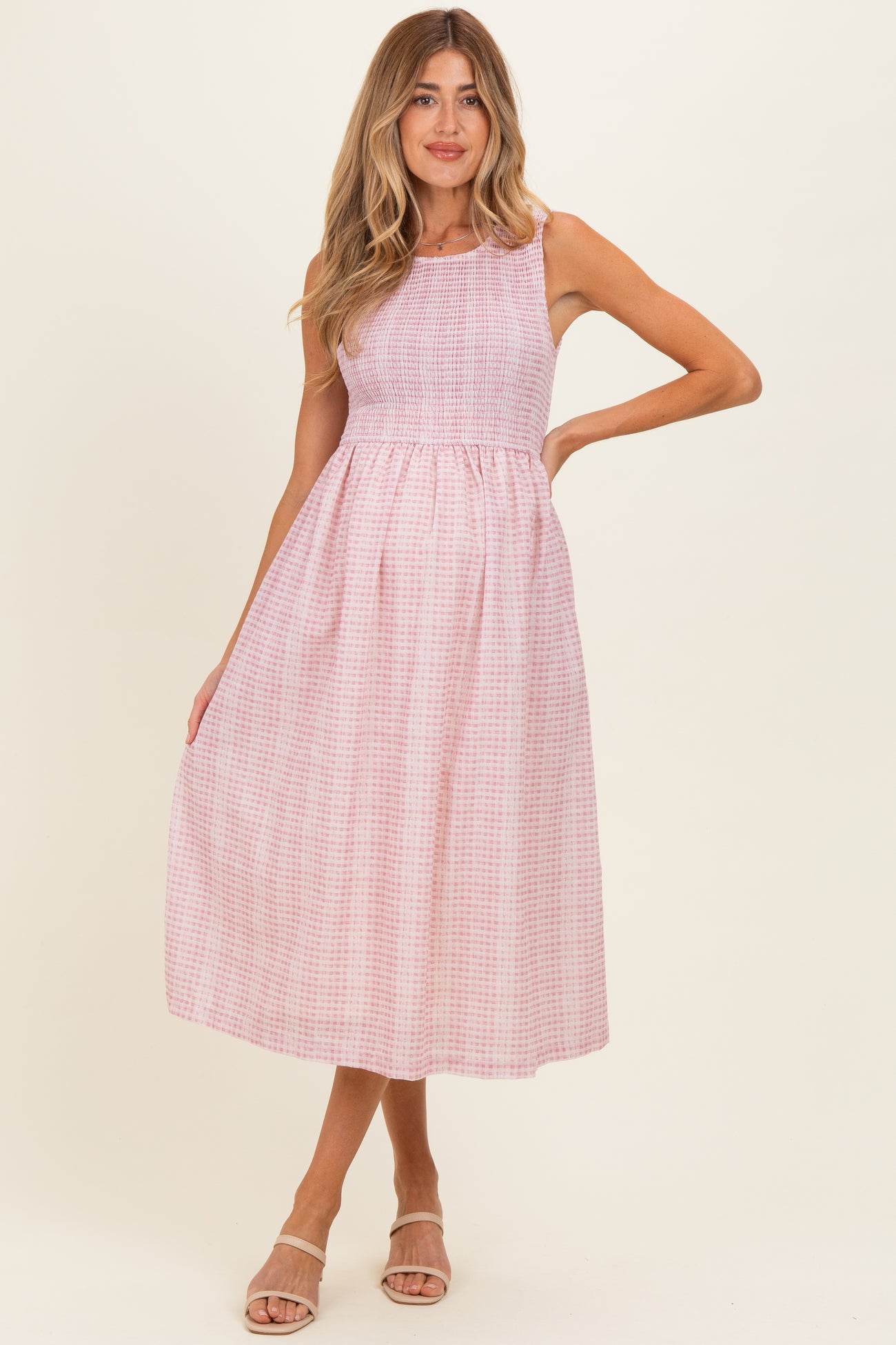 woman wearing a pink and white checkered maternity dress with a fitted bodice and flowing skirt