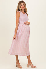 woman wearing a pink and white checkered maternity midi dress and holding her baby bump