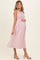 woman wearing a pink and white checkered maternity midi dress and holding her baby bump