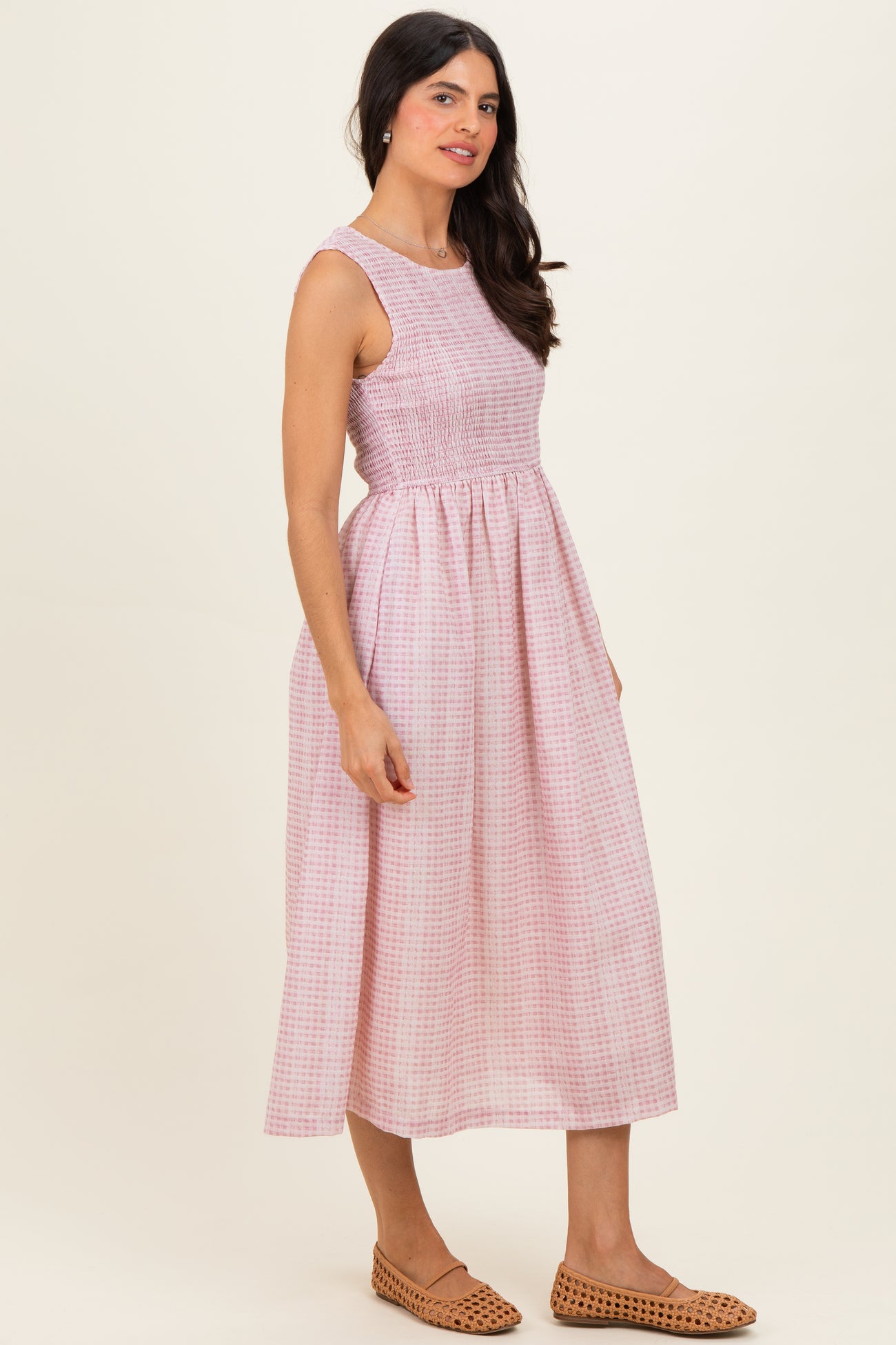 woman wearing a pink and white checkered midi dress with a smocked waist and sandals