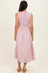 woman wearing a pink and white midi dress with a smocked bodice and a keyhole back detail