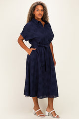 woman wearing a navy blue plus size dress with short sleeves, a tie belt, and floral embroidery details