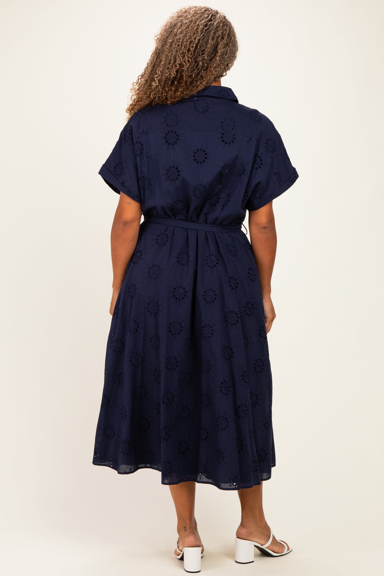 plus size woman wearing a navy blue midi dress with short sleeves and a belt, showing flower cut-out details