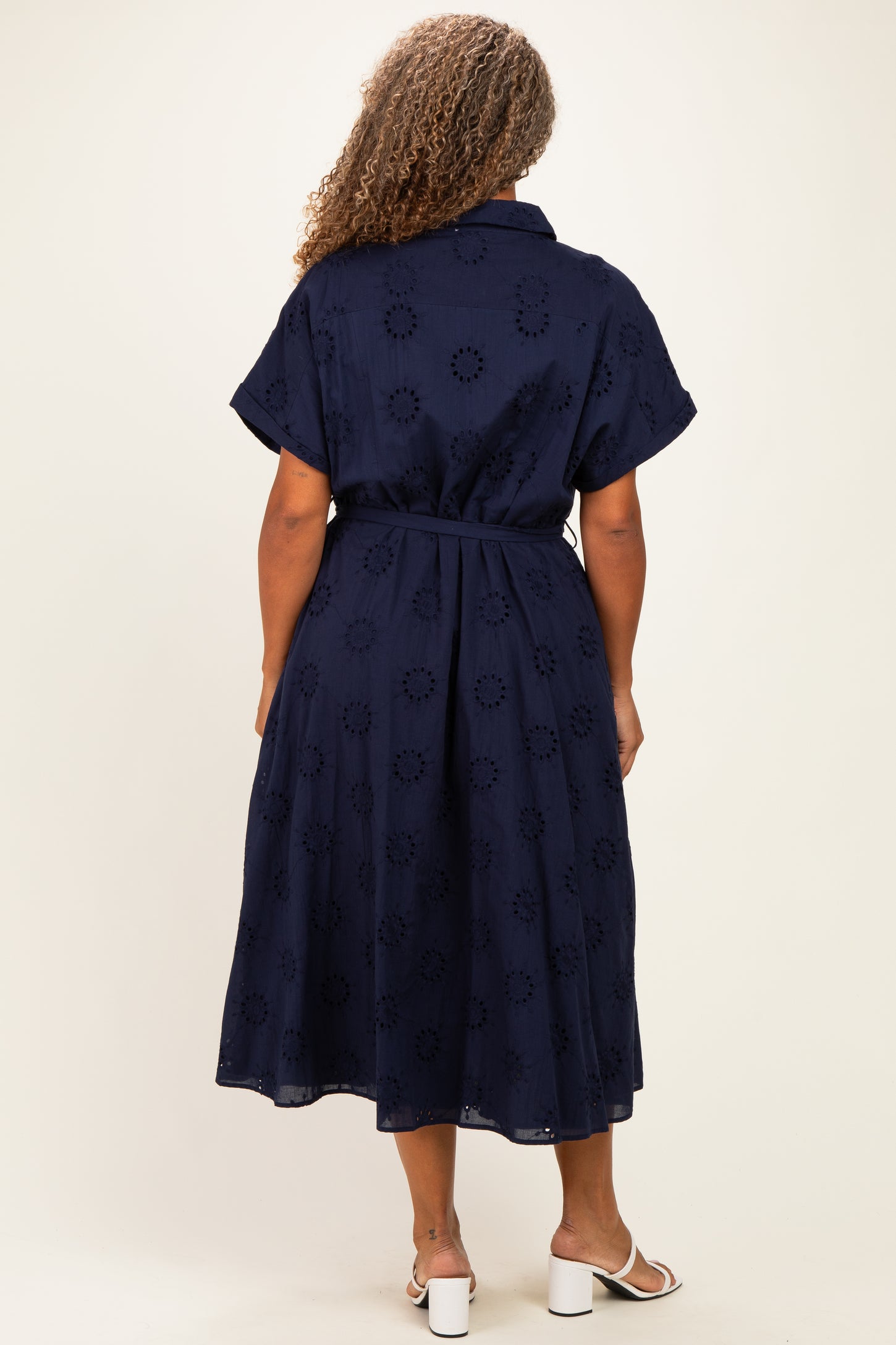 plus size woman wearing a navy blue midi dress with short sleeves and a belt, showing flower cut-out details