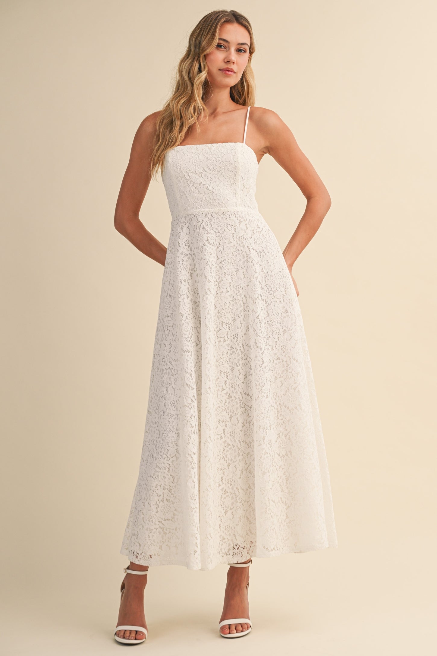 woman wearing a white lace maxi dress with thin straps and a fitted bodice