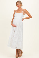 woman wearing a white lace maternity dress with spaghetti straps and holding her baby bump