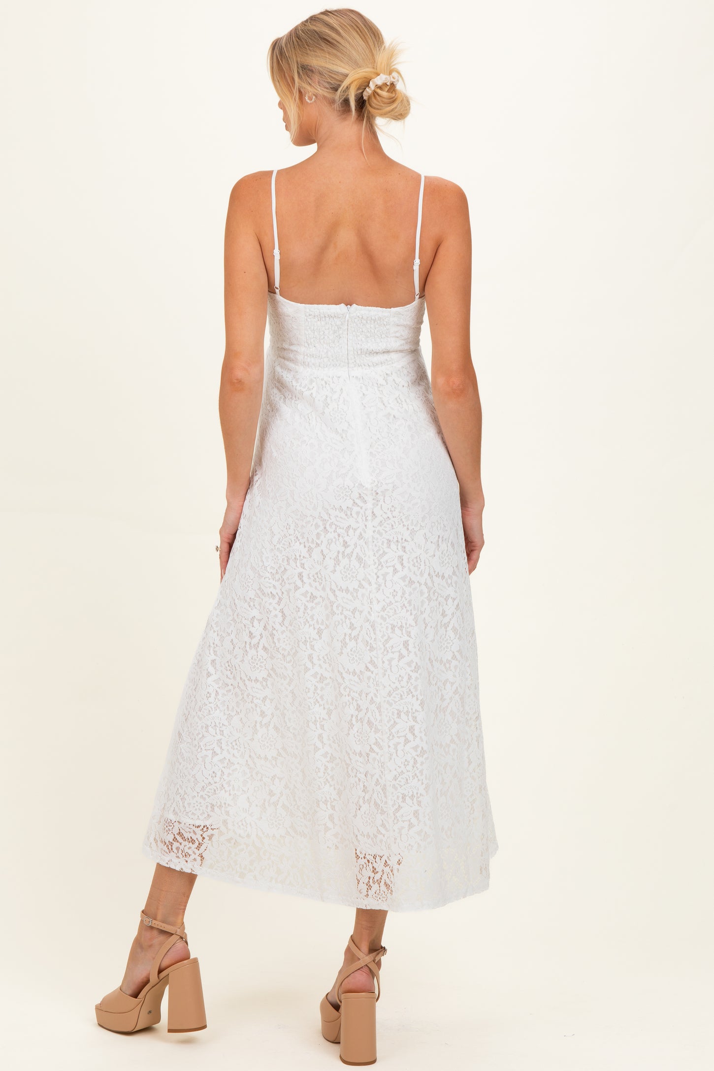 woman wearing a white lace maternity dress with spaghetti straps and a flowy midi length.