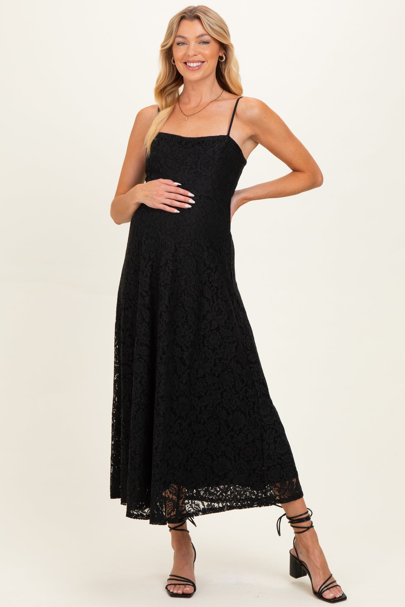 woman wearing a black lace maternity dress with a fitted bodice and flowing skirt, showing her baby bump
