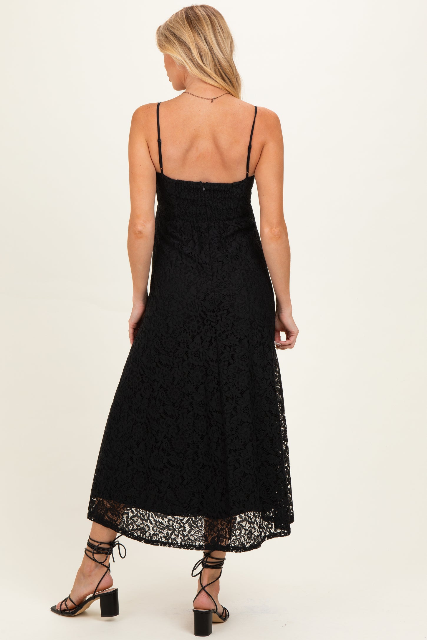 woman wearing a black lace maternity dress with adjustable straps and a flowy hem, showing support for a baby bump