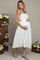 woman wearing a white eyelet maternity dress with cutout details and holding her baby bump