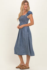 woman wearing a chambray puff sleeve midi dress with a smocked bodice and a flowing skirt