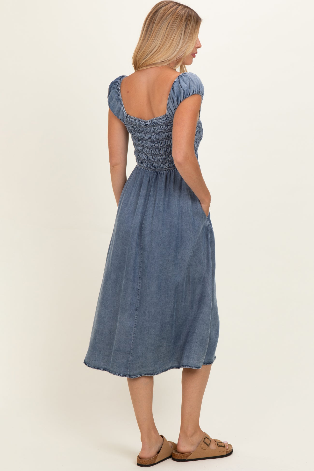 woman wearing a blue denim maxi dress with short puff sleeves and a smocked bodice, showing the back view
