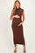 woman wearing a brown ribbed sleeveless maternity dress and holding her baby bump