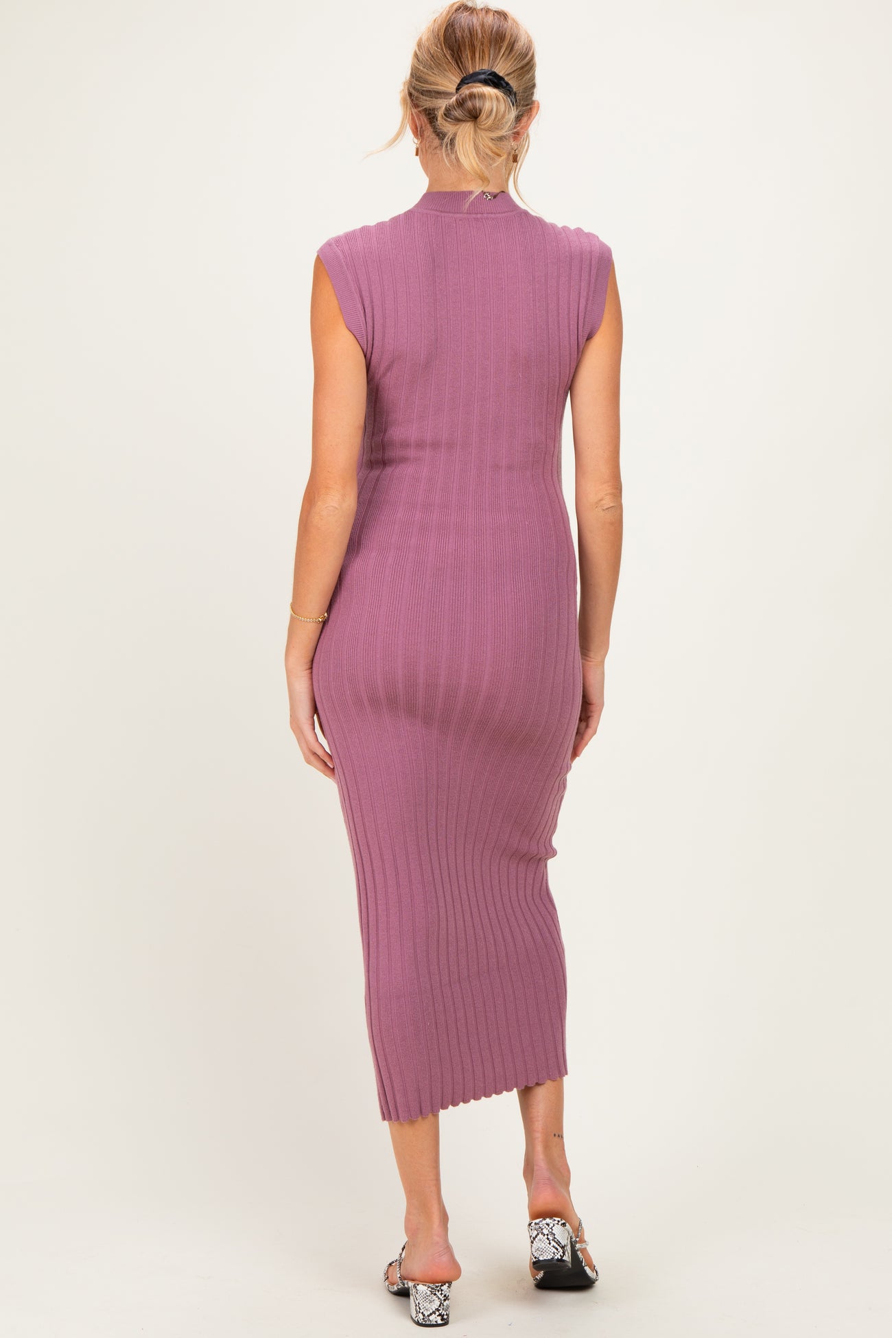 woman wearing a lavender sleeveless ribbed maternity dress, showing a fitted silhouette and midi length from the back