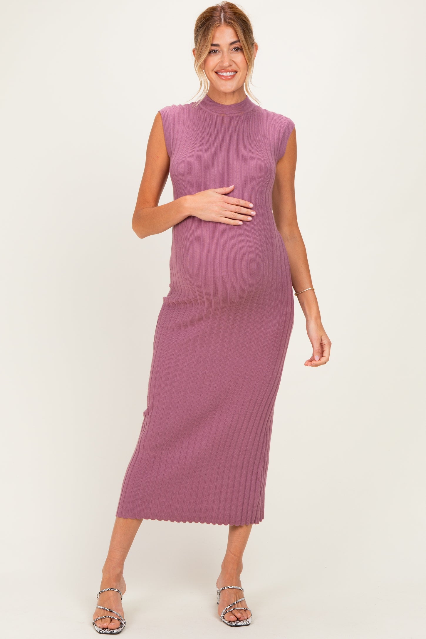 woman wearing a ribbed mauve maternity dress, showing her baby bump, with a knee-length hem and sleeveless design