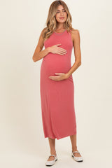 woman wearing a rose pink sleeveless maternity maxi dress and holding her baby bump