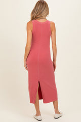 woman wearing a pink sleeveless maternity midi dress with a back slit and a fitted silhouette