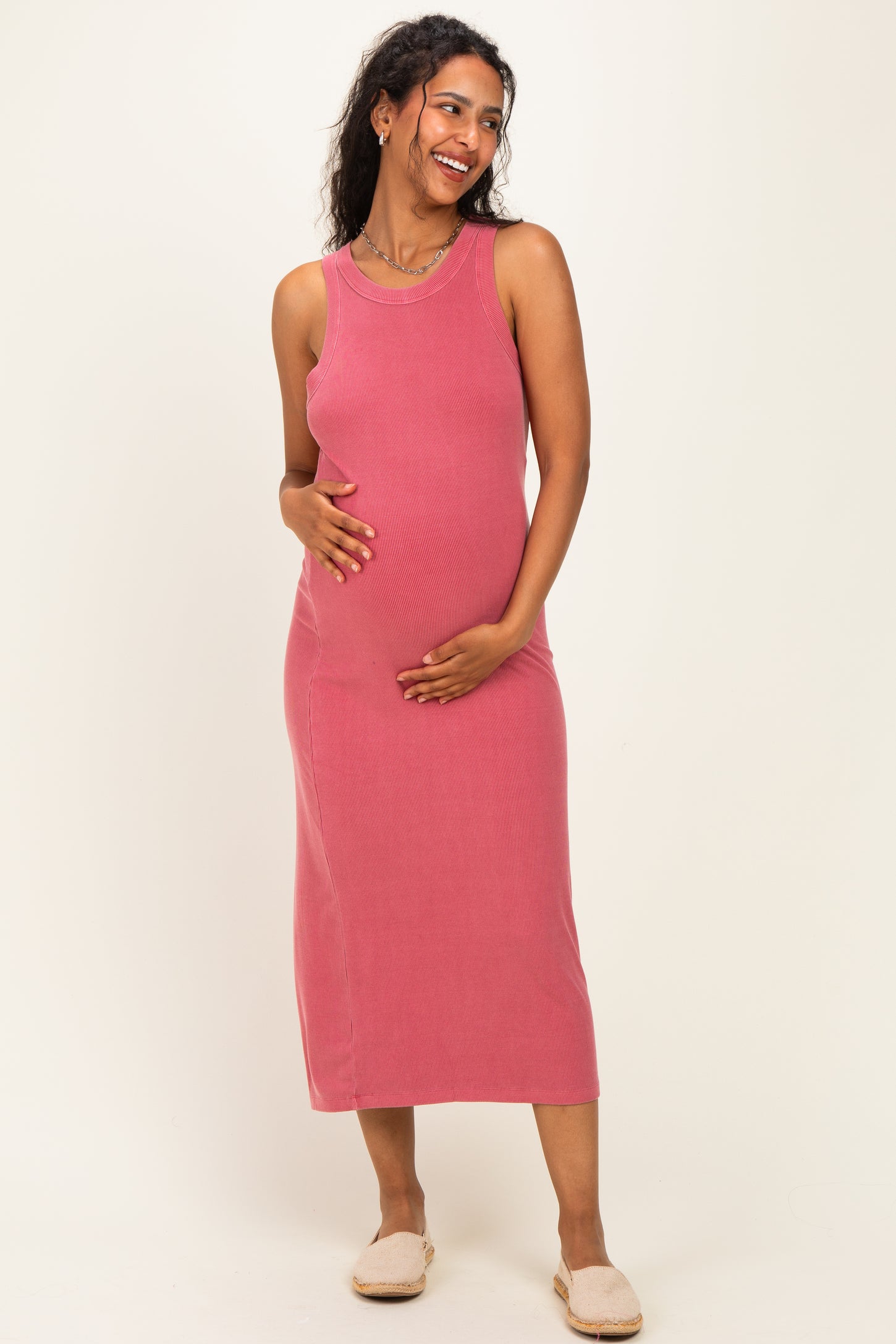 woman wearing a rosy pink ribbed maternity dress and holding her baby bump