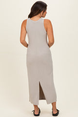 woman wearing a light gray ribbed maternity maxi dress with a back slit, showing a form-fitting silhouette