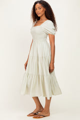 woman wearing a light green smocked bodice midi dress with puff sleeves and tiered skirt