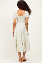 woman wearing a light green tiered maxi dress with a smocked bodice and short puff sleeves, seen from the back