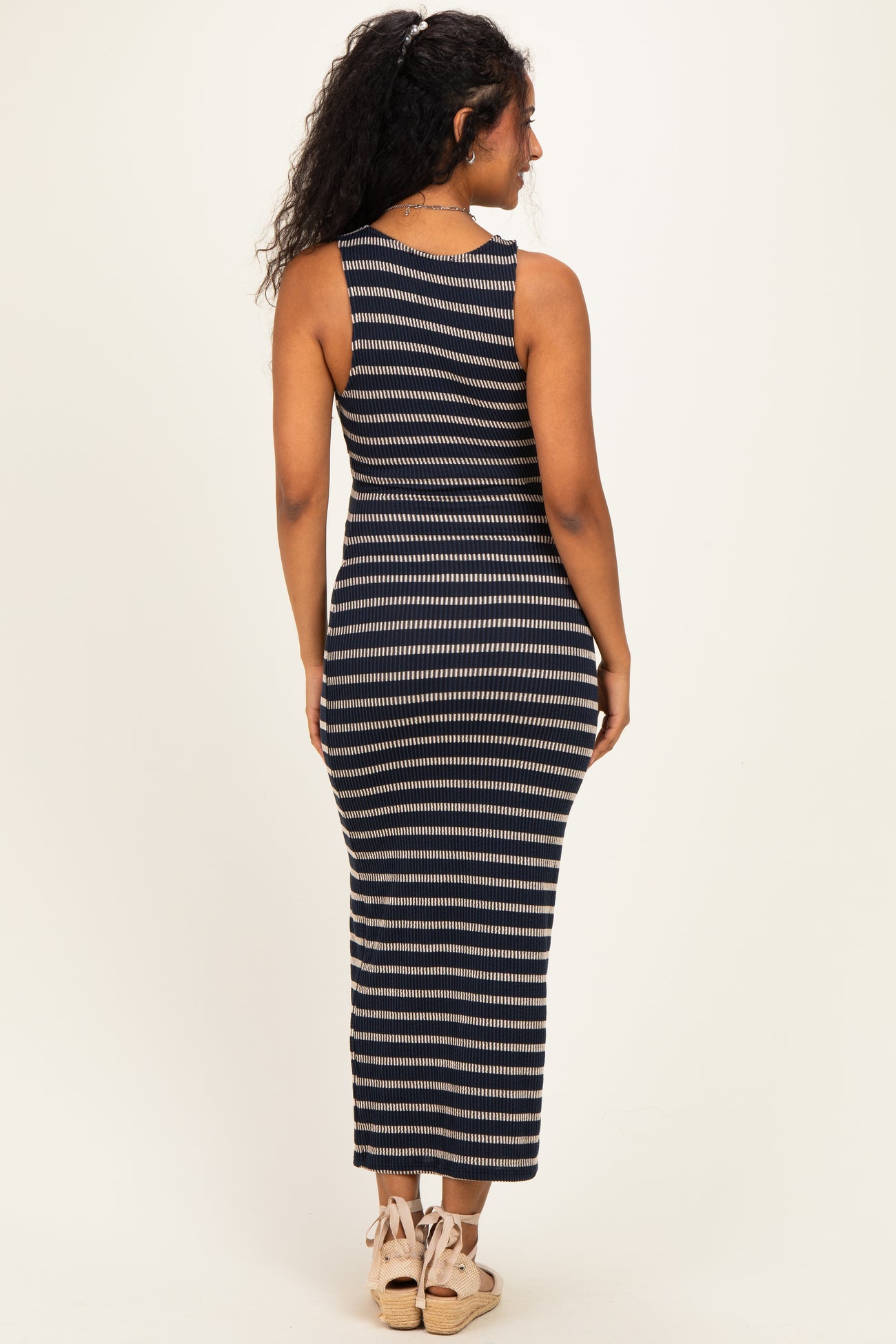 woman wearing a navy and cream striped maternity maxi dress, viewed from the back