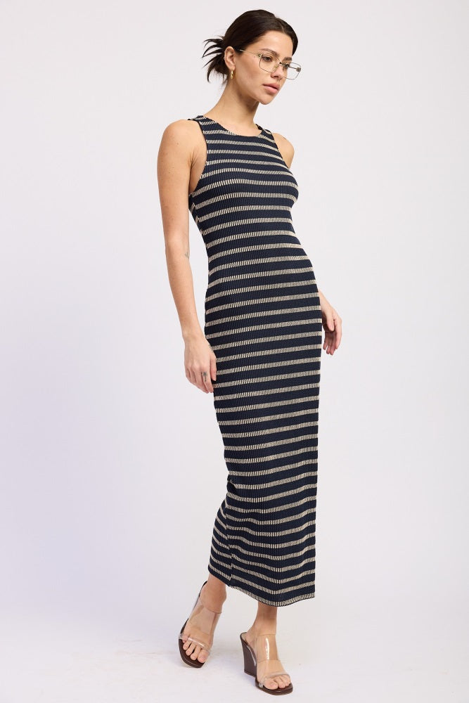 woman wearing a navy and beige striped maxi dress with a fitted silhouette and side slit, paired with clear block-heeled sandals