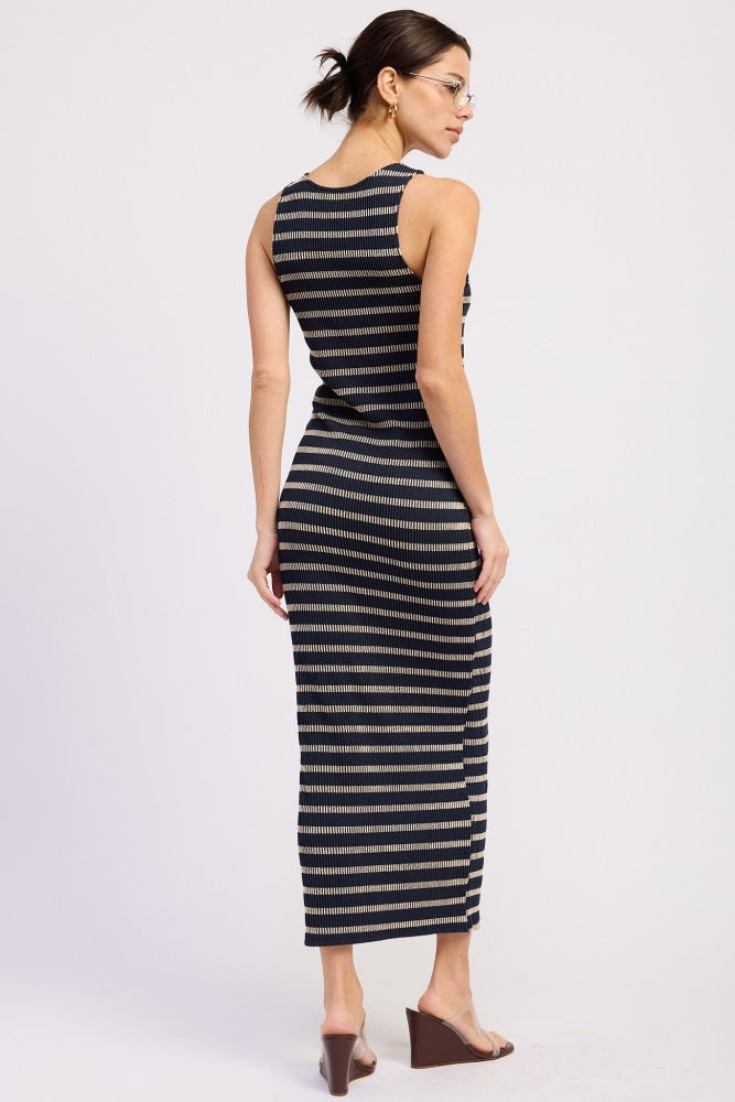 woman wearing a fitted black and beige striped maxi dress, showing the back and side details, with sleek brown heels