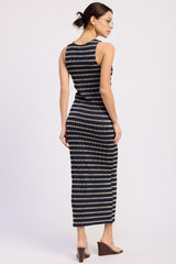 woman wearing a fitted black and beige striped maxi dress, showing the back and side details, with sleek brown heels
