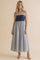 woman wearing a navy and white polka dot tie strap maxi dress with a striped skirt
