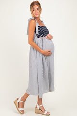 woman wearing a navy and white striped maternity dress with polka dot details and holding her baby bump