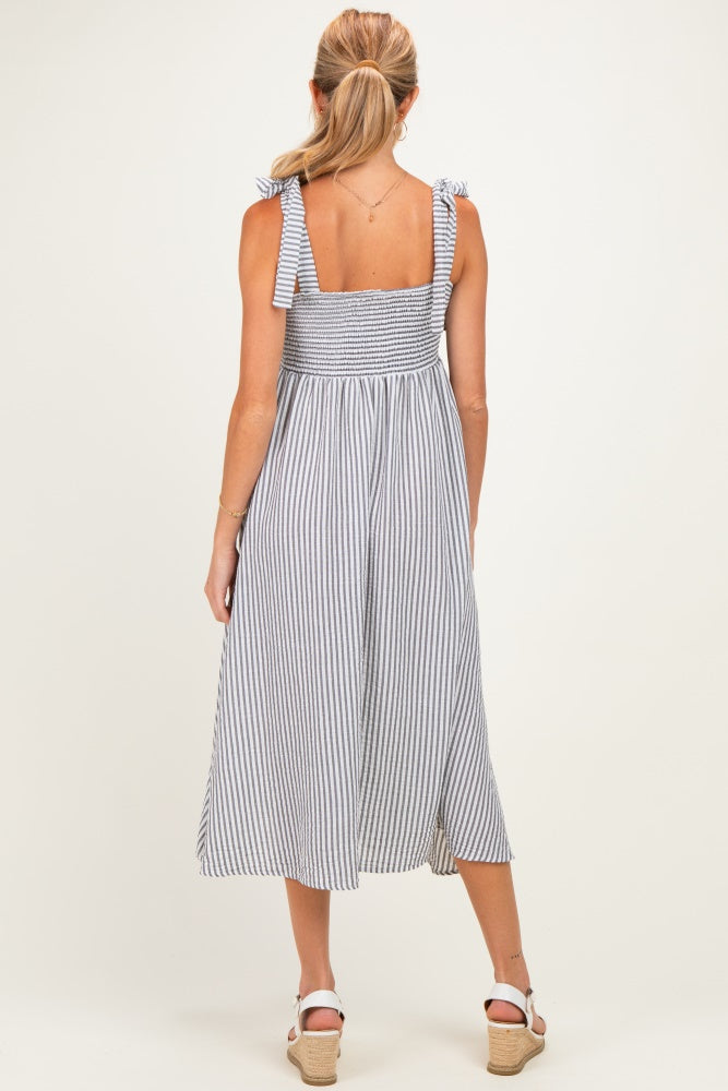 woman wearing a striped maternity dress with tie straps and a flowing skirt, showing a baby bump from the back