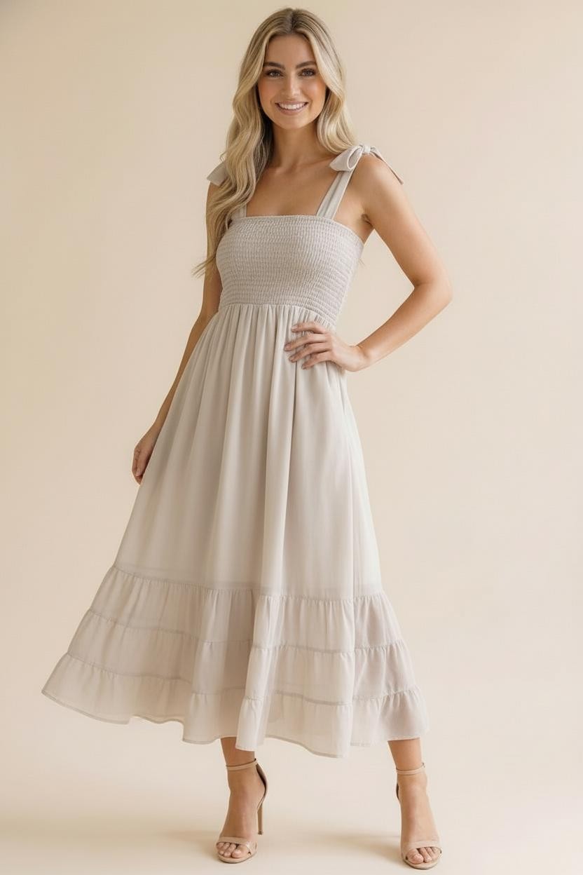 woman wearing a light beige mid-length dress with smocked bodice and tie straps, styled with strappy heels
