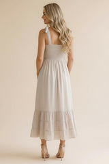 woman wearing a light beige midi dress with a smocked bodice and ruffled hem, showing the back view