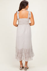 woman wearing a light grey maternity dress with smocked bodice and ruffled hem, shown from the back