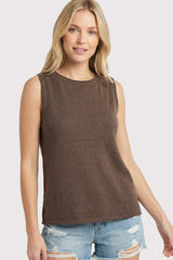 woman wearing a brown sleeveless top with a round neckline and paired with distressed denim shorts