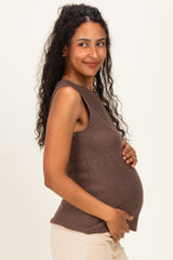 woman wearing a brown sleeveless maternity top and holding her baby bump
