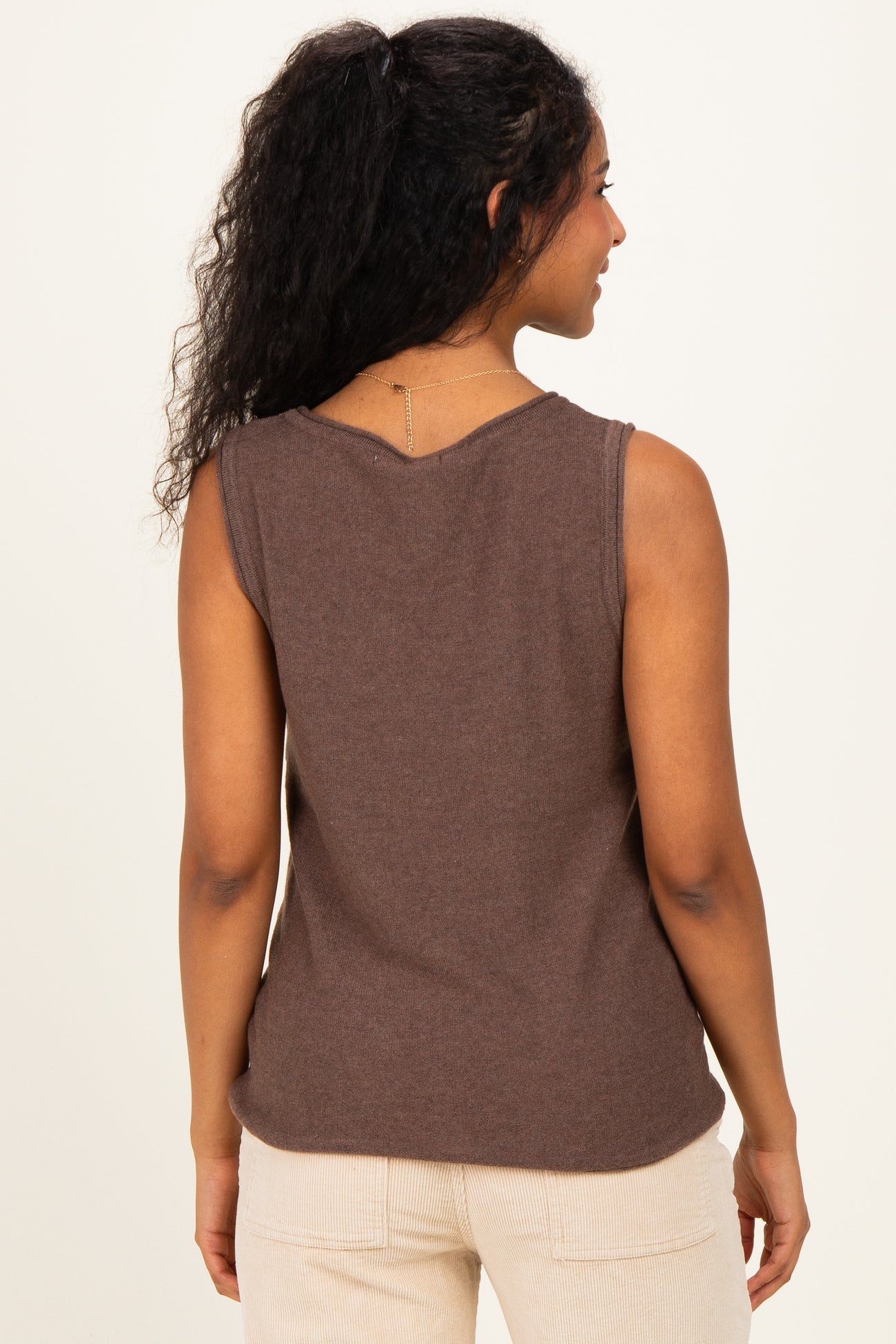 woman wearing a brown sleeveless maternity top, viewed from the back