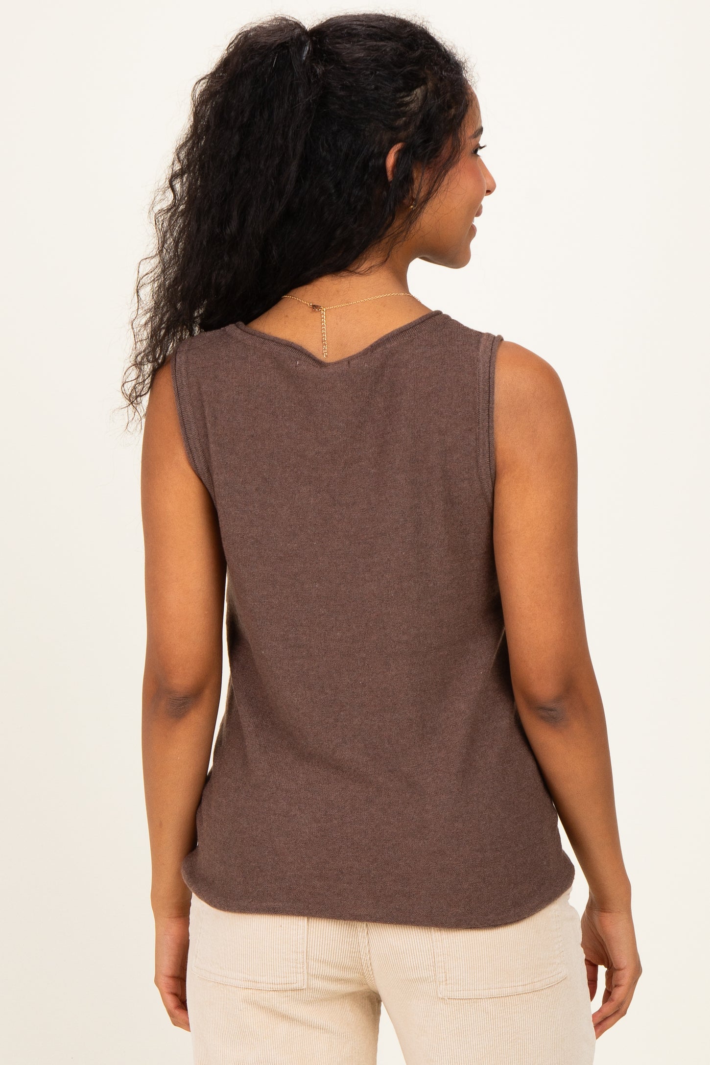 woman wearing a brown sleeveless maternity top, viewed from the back